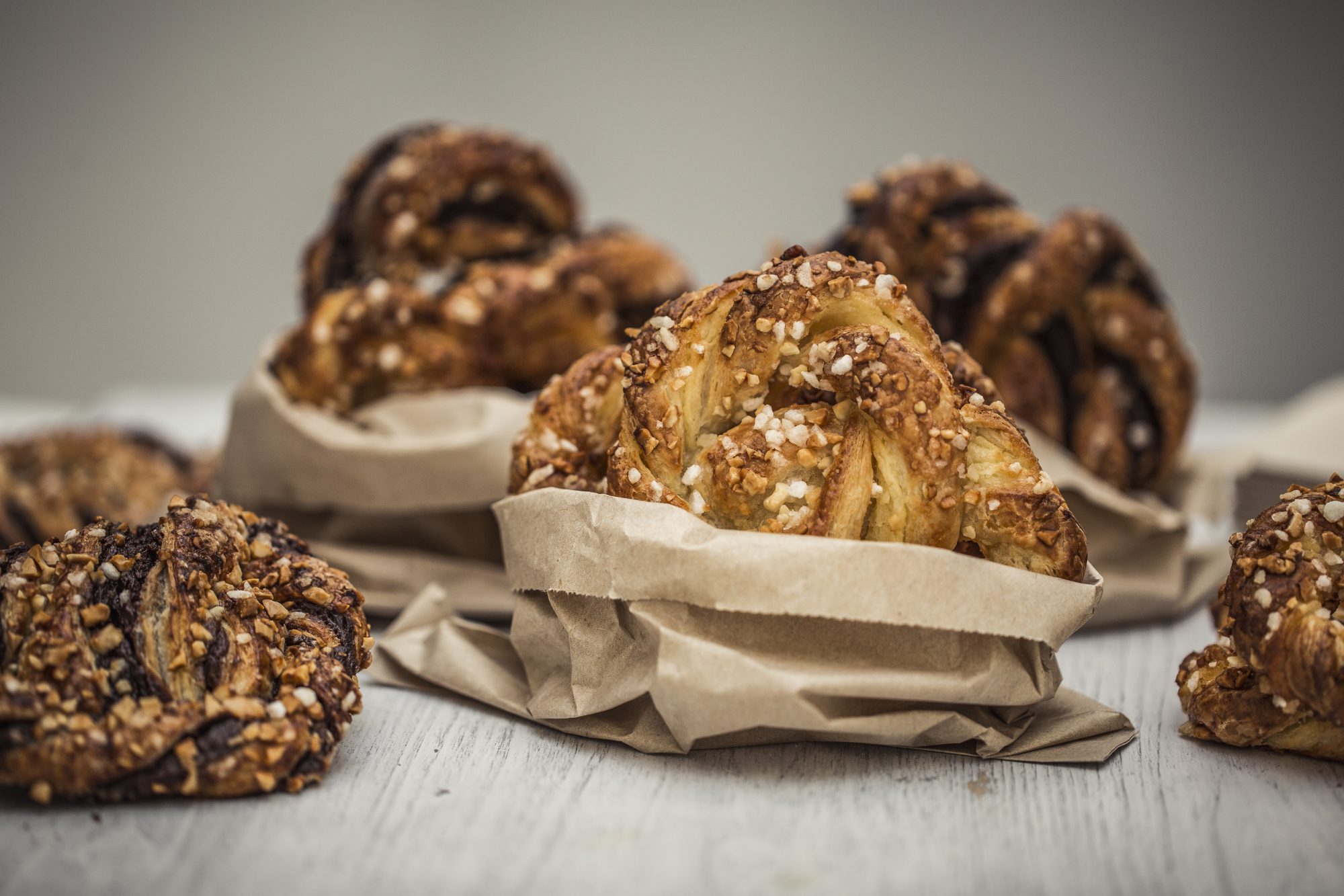 The Emma-Jane's almond and custard Bretzel (or Brezels in German!) wrapped in a brown paper bag, in the background their are chocolate bretzels surrounding it.